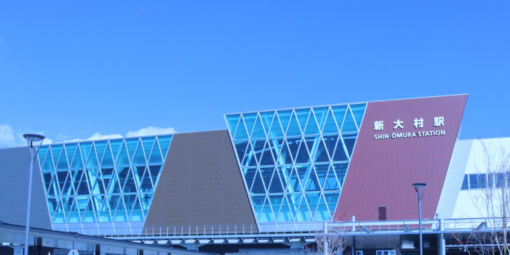 新大村駅の外観。ガラス張りの現代的な駅舎と青空が広がる風景