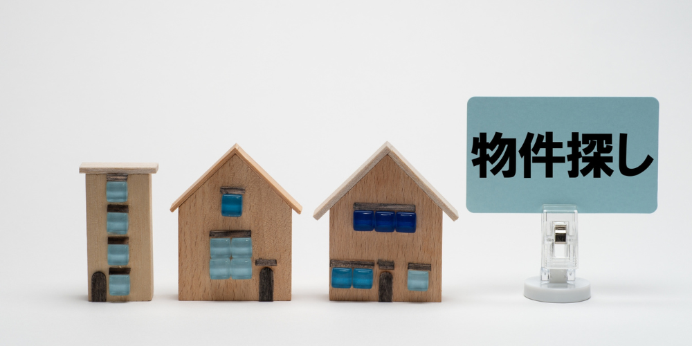 小さな家の模型と「物件探し」の文字が並ぶ構図