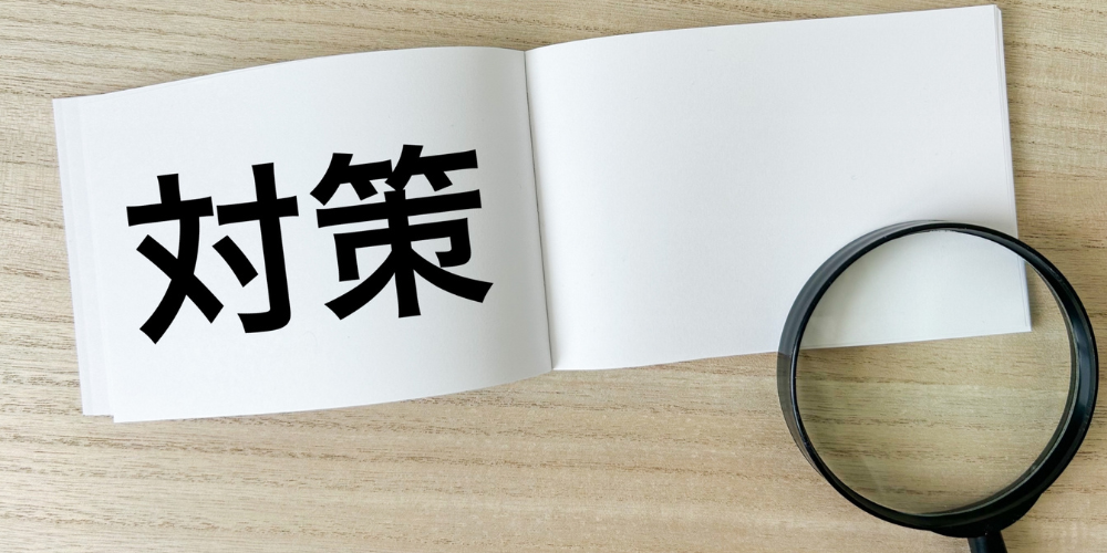 「対策」と書かれたノートと拡大鏡が置かれた木目のデスク