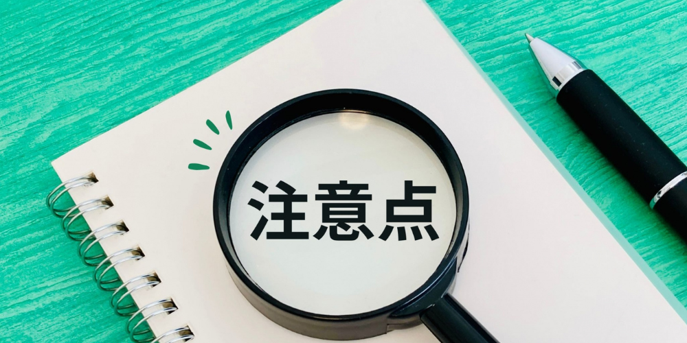 ノートとペンの上に置かれた虫眼鏡に「注意点」と書かれたメモ