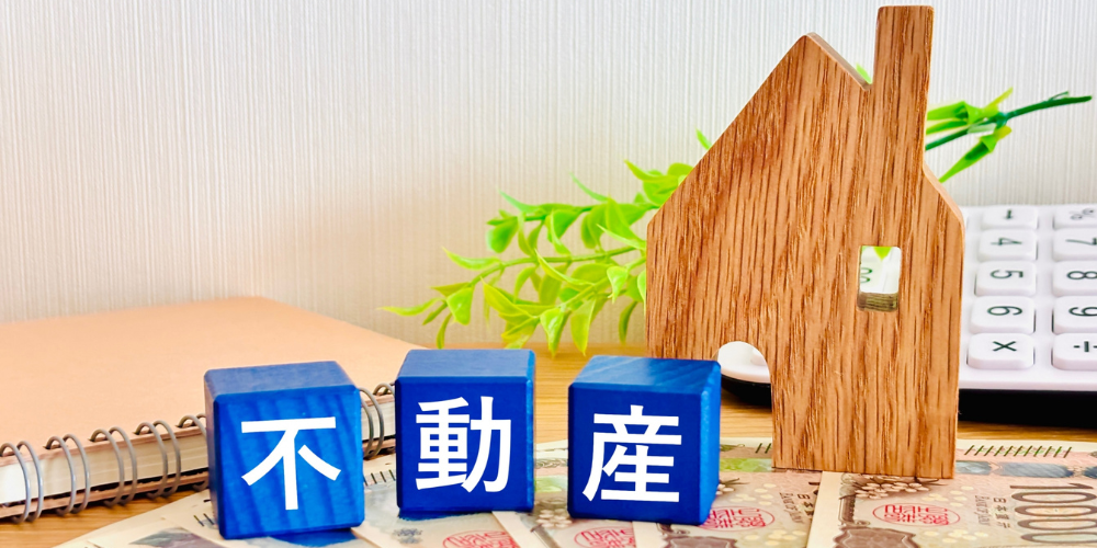 木製の家とお金、そして「不動産」と書かれた青いブロック