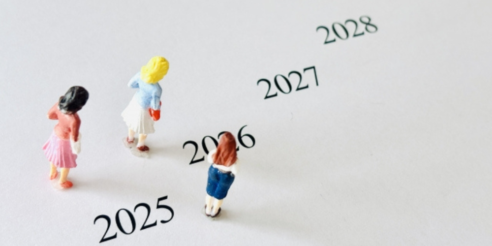 2025年から2028年にかけての年号が並び、フィギュアが未来に向かって歩いているイメージ