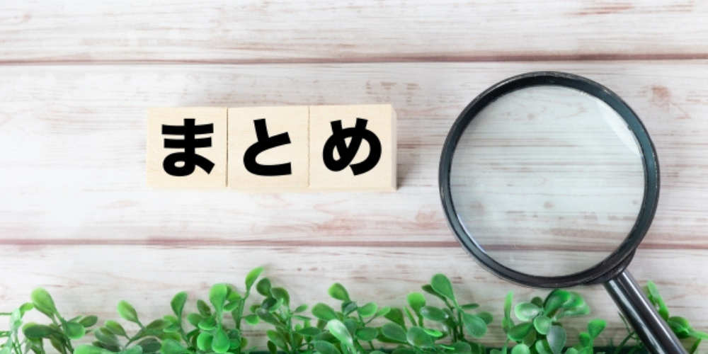 木目調の背景に「まとめ」と書かれたブロックと虫眼鏡、観葉植物が置かれている