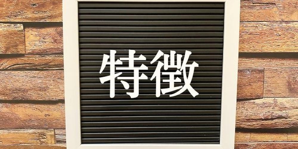 「“特徴”の文字が書かれた黒板風のフレームが木目背景に掛けられている」