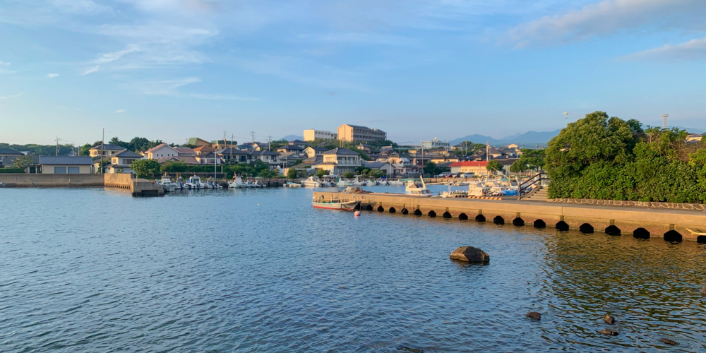 長崎県大村市の穏やかな港町の夕景─防波堤と停泊する小型漁船、背後に住宅街が広がる海辺の風景