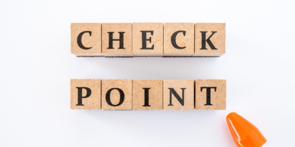 「CHECK POINT」と書かれたブロックとオレンジのペン先が並んだ白背景の画像