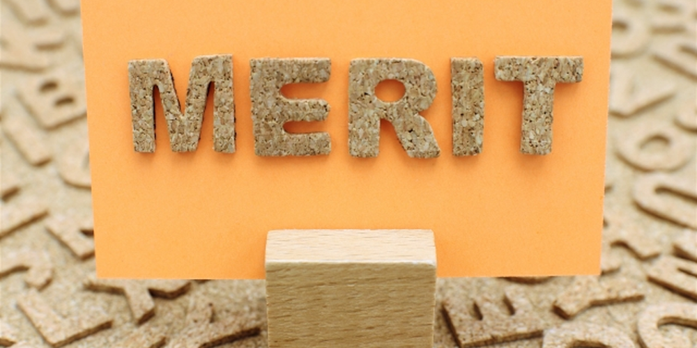 コルク素材の文字で『MERIT』と書かれたオレンジのカード、メリットや利点を示すイメージ