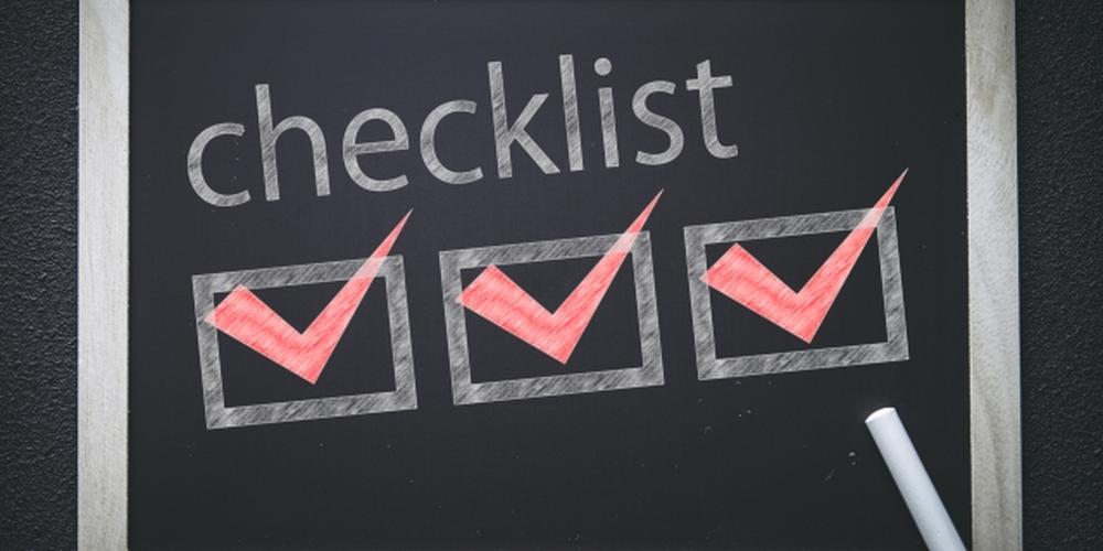 「“checklist”の文字と3つの赤いチェックマークが描かれた黒板とチョーク」