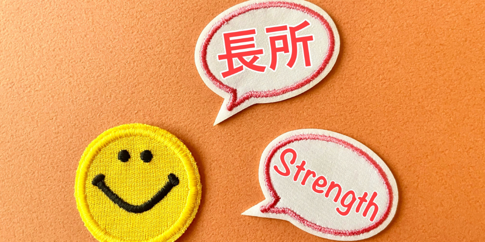 スマイリーフェイスの横に「長所」と「Strength」と書かれた吹き出しのワッペン
