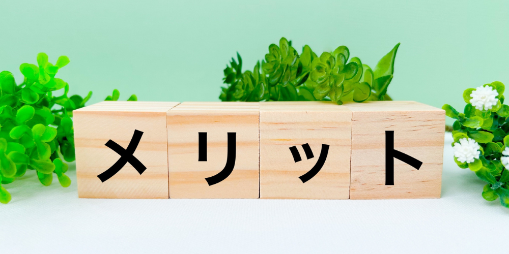 木製ブロックで並べた「メリット」と緑の葉