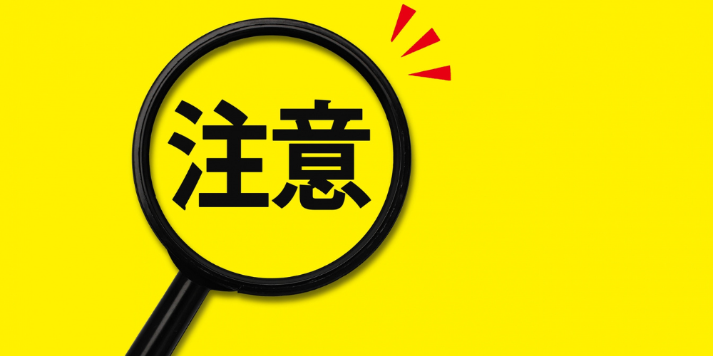 黄色背景に虫眼鏡で強調された「注意」