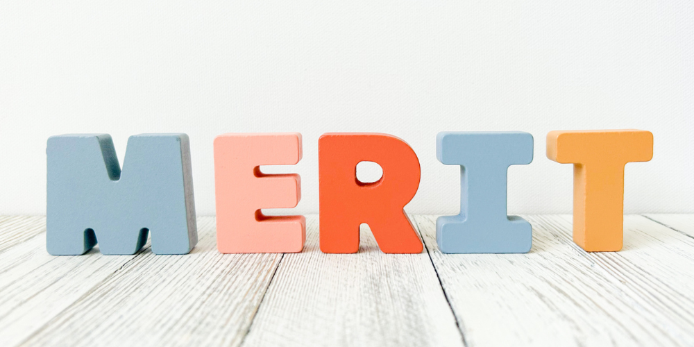 「MERIT」の文字がカラフルな木製ブロックで並べられている画像