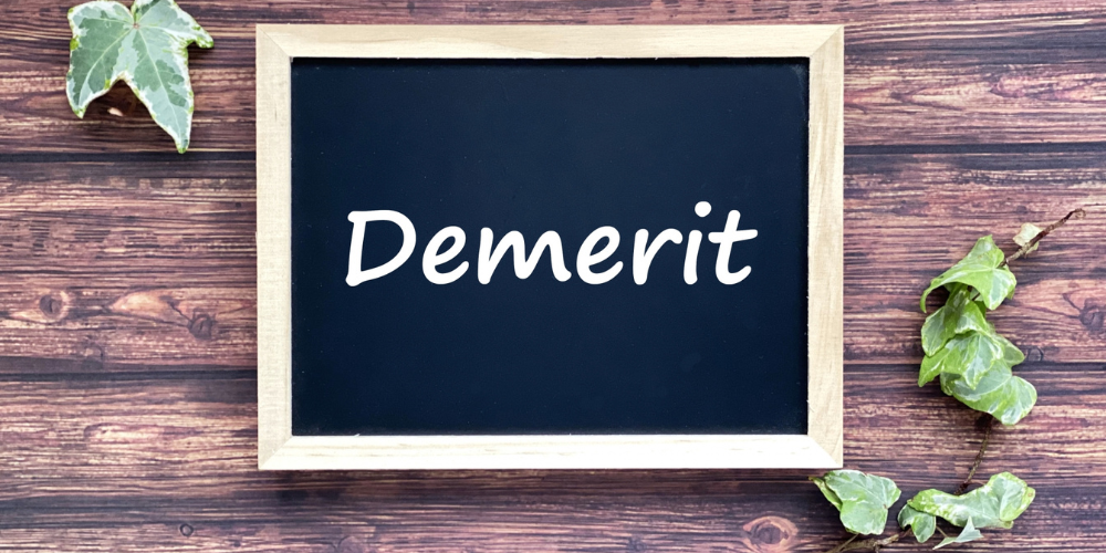 木製フレームの小さな黒板に白文字で「Demerit」と書かれ、周囲をアイビーの葉が彩るシンプルなデメリットイメージ
