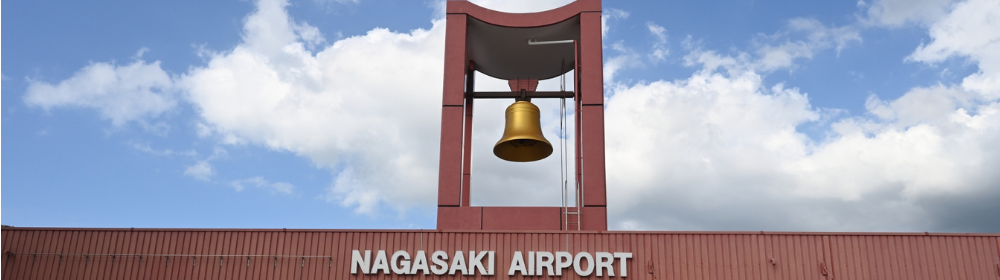 青空の下、鐘をつり下げた赤いタワーと「NAGASAKI AIRPORT」のサインが目を引く長崎空港外観
